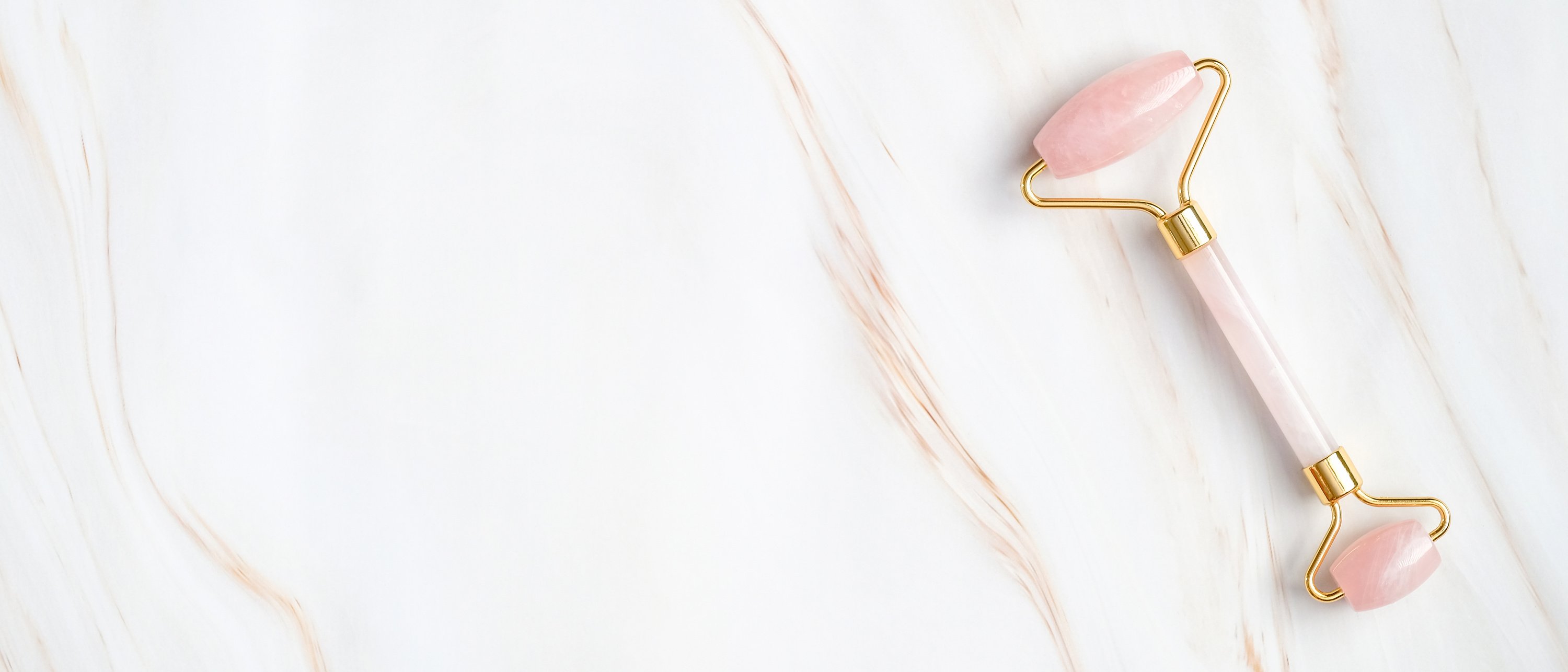 Rose Quartz Face Roller on a Marble Background